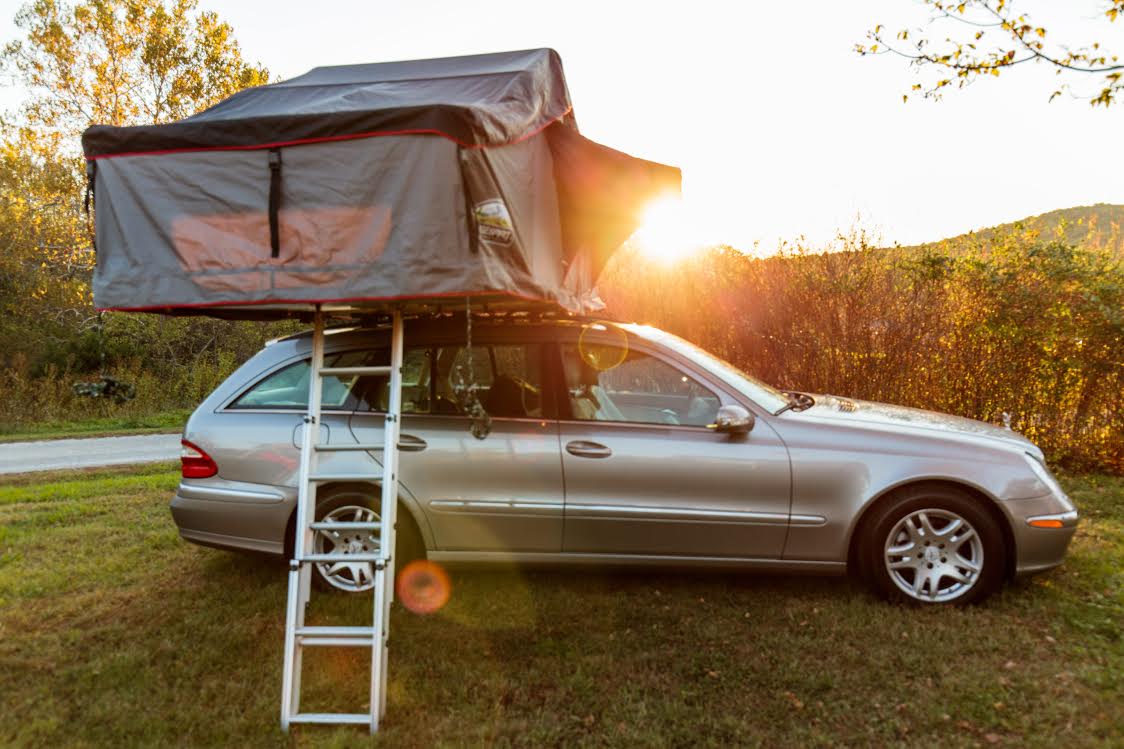Tienda de techo desplegada sobre un coche en un camping