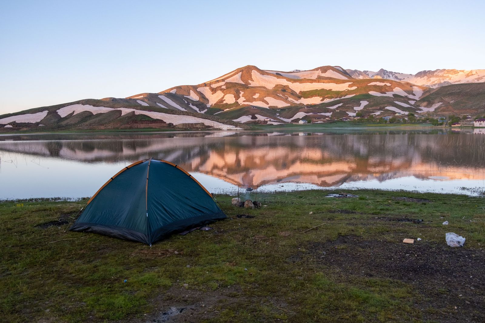 Tienda junto a un lago de montaña al amanecer